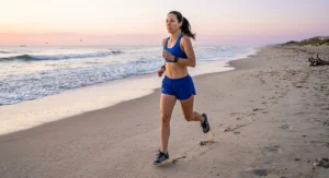 Woman jogging near the ocean waves at sunrise wearing flexible barefoot minimalist running shoes for women.