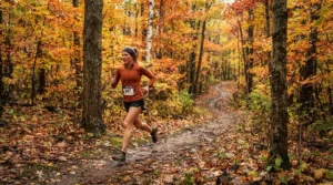 Runner navigating a winding woodland trail in cross country spikes covered in leaves