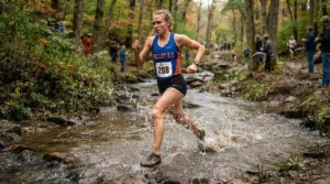 Runner splashing through a shallow creek wearing lightweight cross country spikes