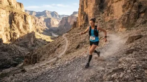 A runner descending a loose gravel slope in men's trail running shorts for rough terrain within a deep desert canyon.